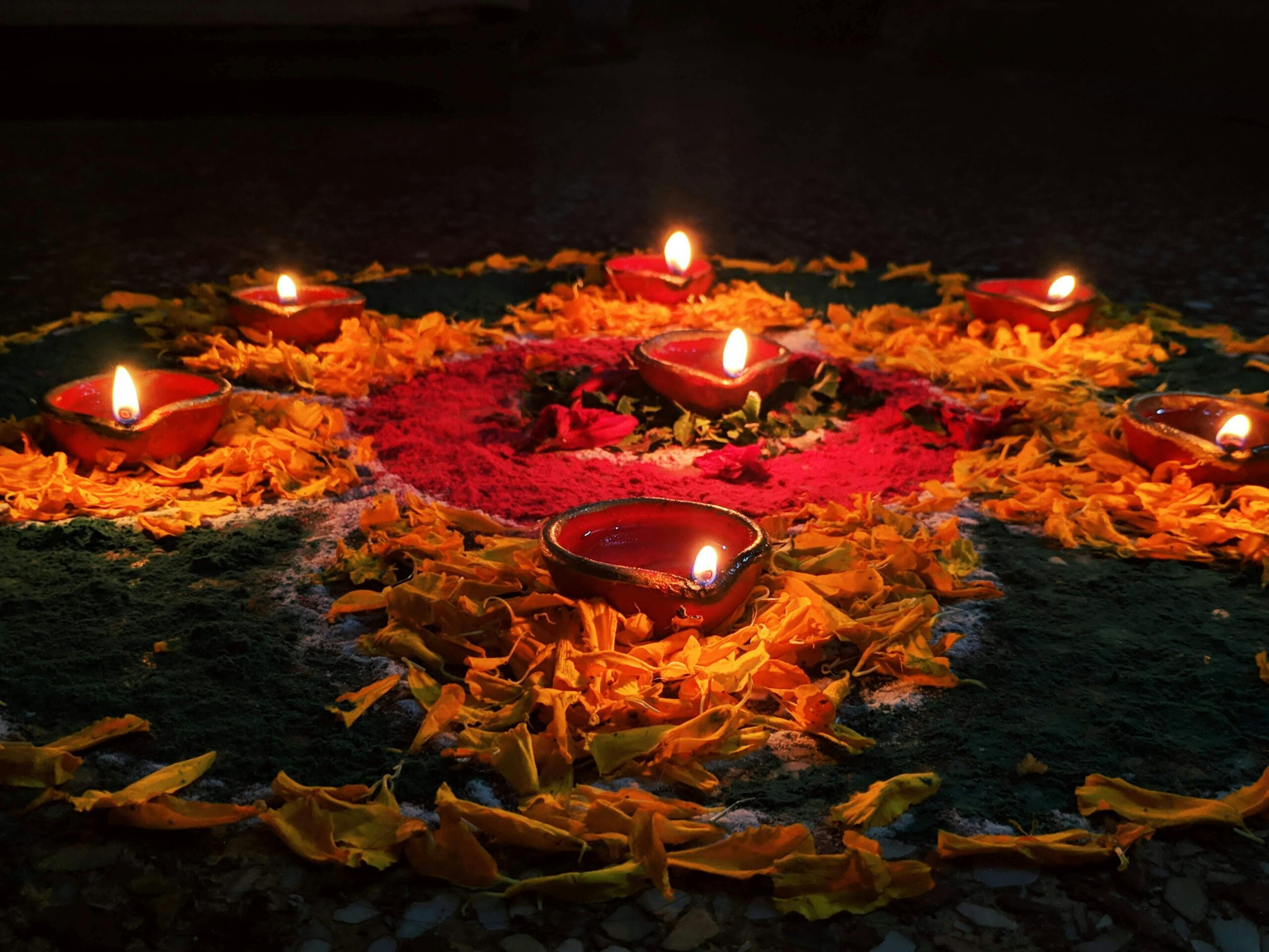 Vibrant Diwali rangoli with glowing oil lamps and flowers in New Delhi.